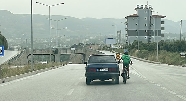 Hatay’da otomobile tutunarak giden bisikletlinin tehlikeli yolculuğu kamerada